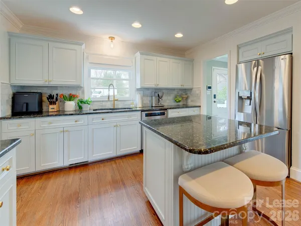 a kitchen with granite countertop a sink a window cabinets and stainless steel appliances