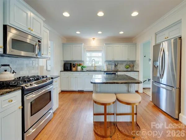 a kitchen with stainless steel appliances granite countertop a stove a sink a refrigerator and a microwave