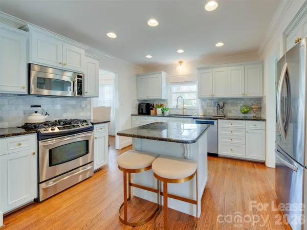 a kitchen with stainless steel appliances a stove a sink a microwave a refrigerator and cabinets