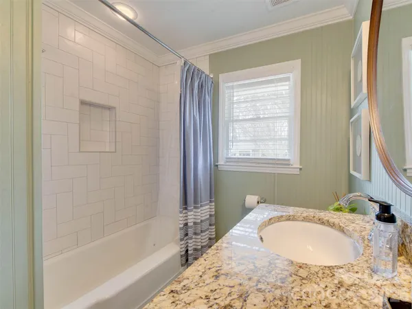 a bathroom with a granite countertop bathtub sink vanity and shower