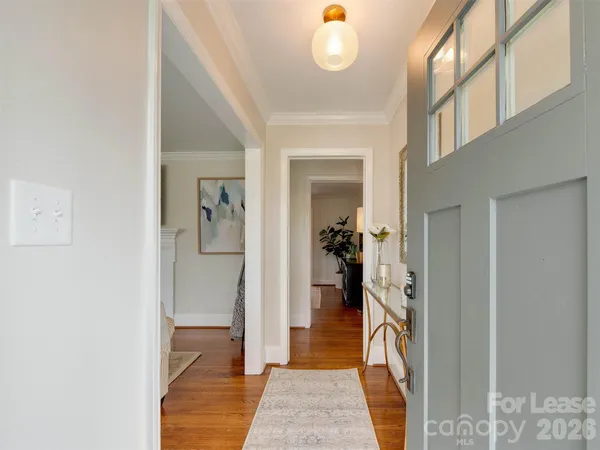 a view of a hallway with wooden floor and a bathroom