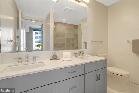 a bathroom with a sink a toilet a mirror and shower