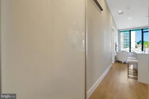 a view of a hallway with wooden floor and a bathroom