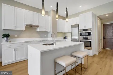 a kitchen with stainless steel appliances white cabinets a sink and a refrigerator