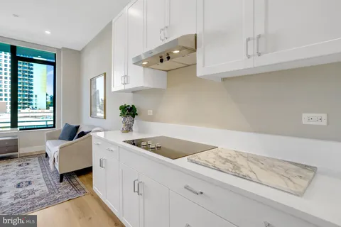 a kitchen with stainless steel appliances granite countertop a sink dishwasher a stove a dining table and chairs with white cabinets