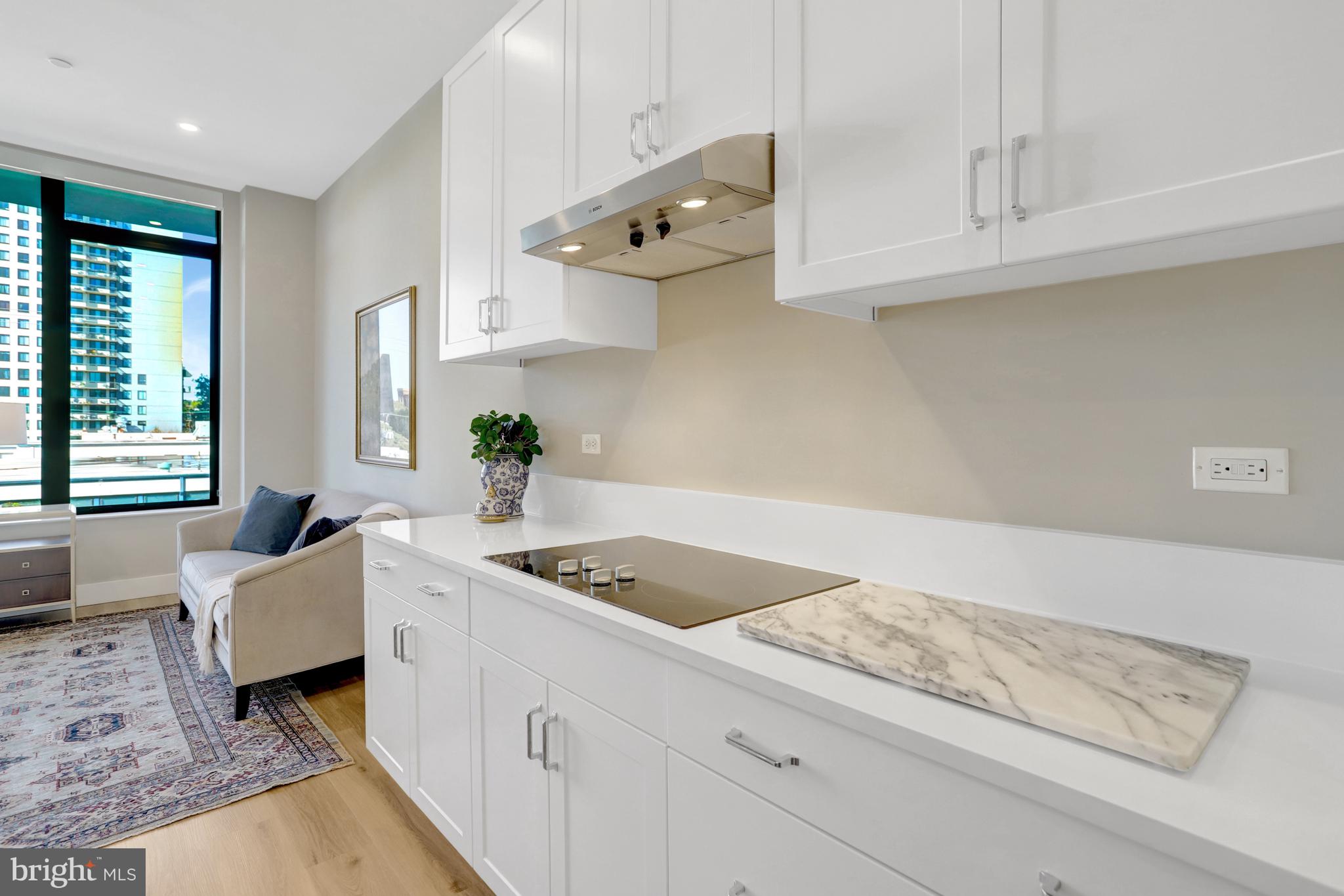 801 North Fairfax Street, Unit 314 Alexandria, VA 22314 - Photo 8 of 61 a kitchen with stainless steel appliances granite countertop a sink dishwasher a stove a dining table and chairs with white cabinets