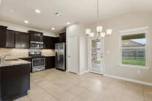 a kitchen with stainless steel appliances granite countertop a sink a stove a refrigerator cabinets and a window