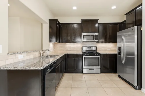 a kitchen with kitchen island granite countertop a stove sink and refrigerator