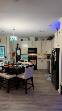 a kitchen with a refrigerator a stove and a dining table with wooden floor