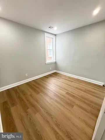 a spacious bedroom with a bed and wooden floor