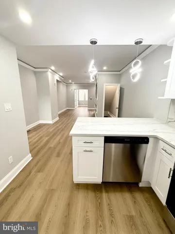a large white kitchen with a large counter top space a sink and stainless steel appliances