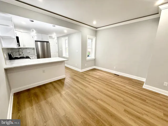 a large white kitchen with wooden floor and a sink