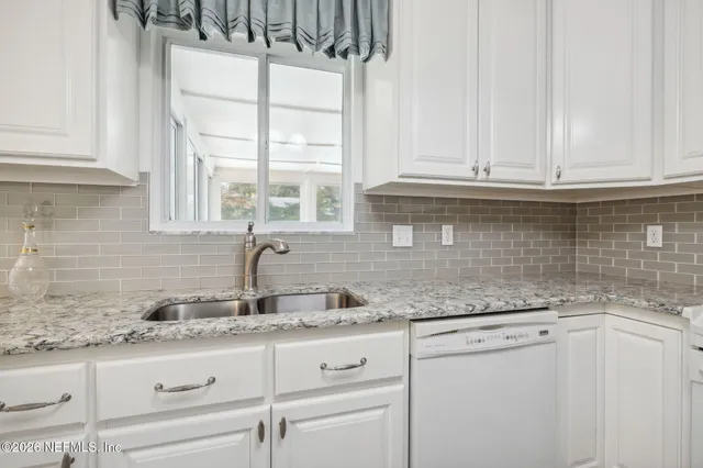 a kitchen with granite countertop white cabinets and a sink