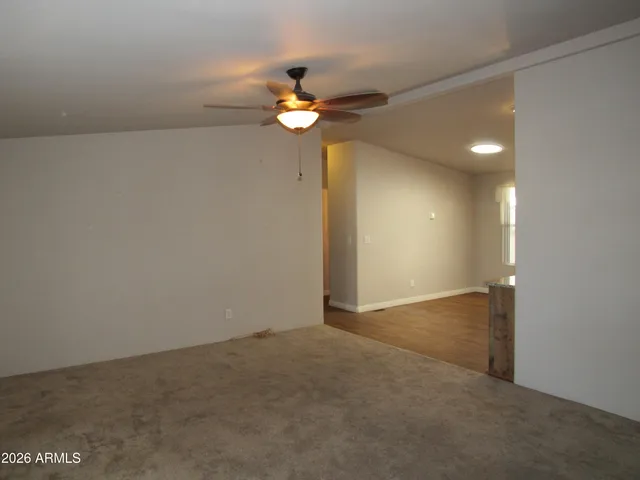 a view of an empty room with chandelier fan and a window