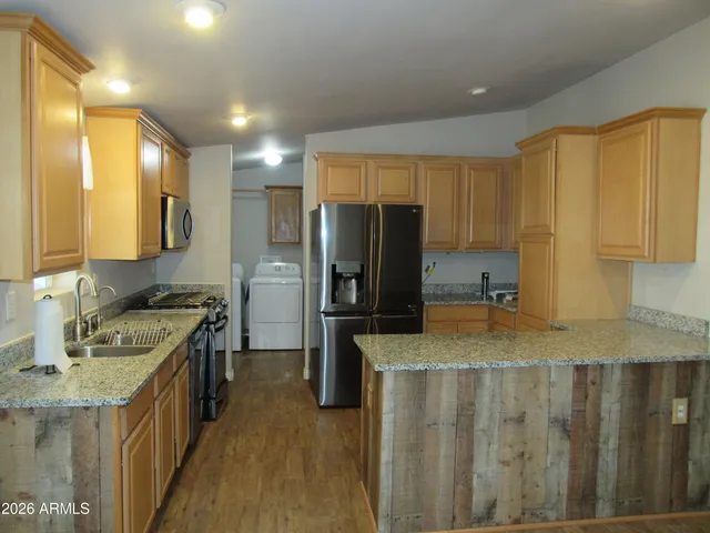 a kitchen with stainless steel appliances granite countertop a refrigerator a stove and a sink