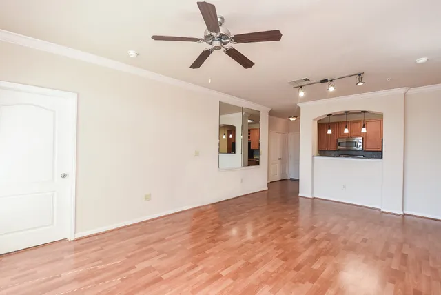 an empty room with wooden floor and ceiling fan