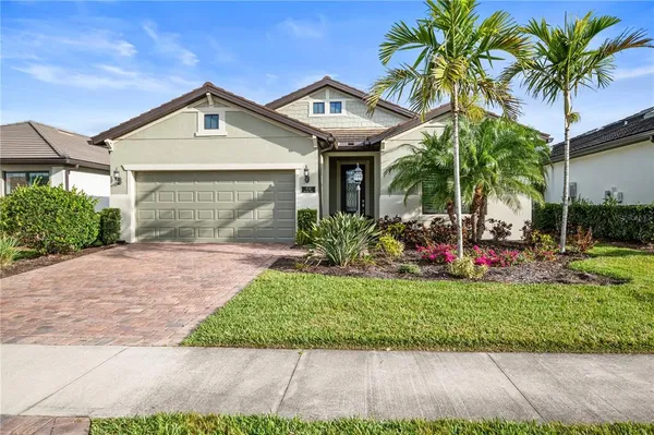 a front view of a house with a garden and palm trees