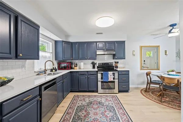 a kitchen with stainless steel appliances granite countertop a stove top oven a sink dishwasher and cabinets with wooden floor