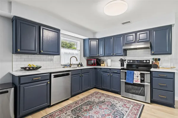 a kitchen with stainless steel appliances granite countertop a stove sink and cabinets