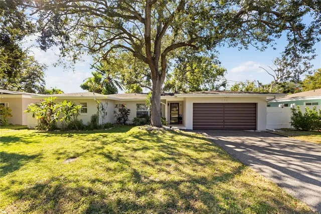 a view of a house with a large tree and a yard