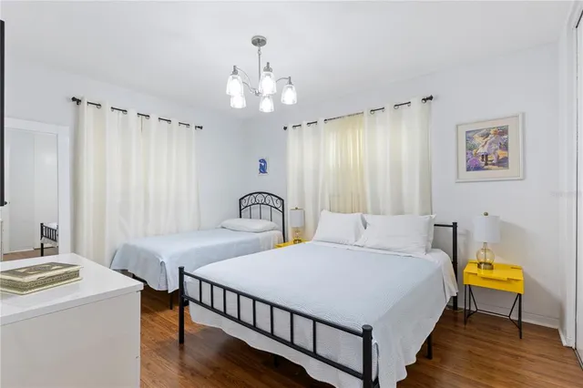 a spacious bedroom with a bed a chandelier and a dresser