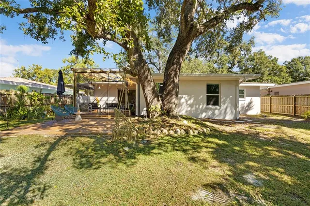 a view of a yard with plants and large tree
