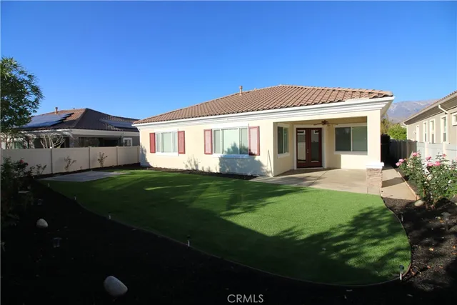 a view of a white house with a big yard potted plants and large tree