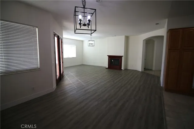 an empty room with wooden floor closet and windows