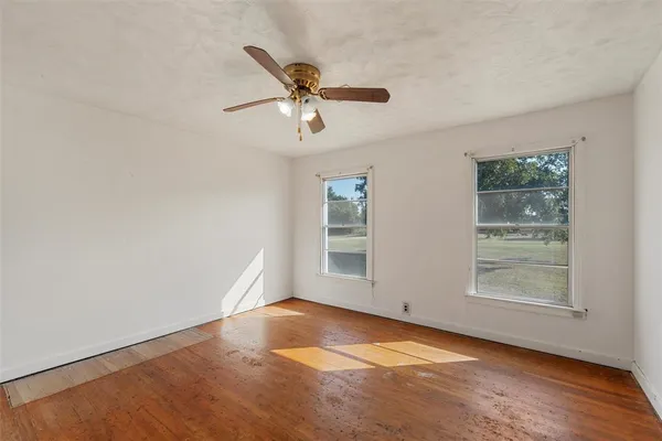 an empty room with windows and fan