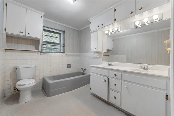 a bathroom with a double vanity sink a toilet a mirror and bathtub