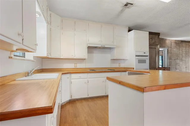 a kitchen with a sink a stove a refrigerator and white cabinets