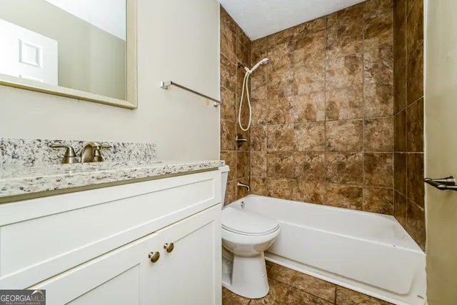 a bathroom with a granite countertop sink toilet and shower