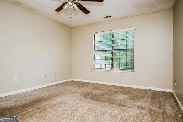 an empty room with a window and a ceiling fan