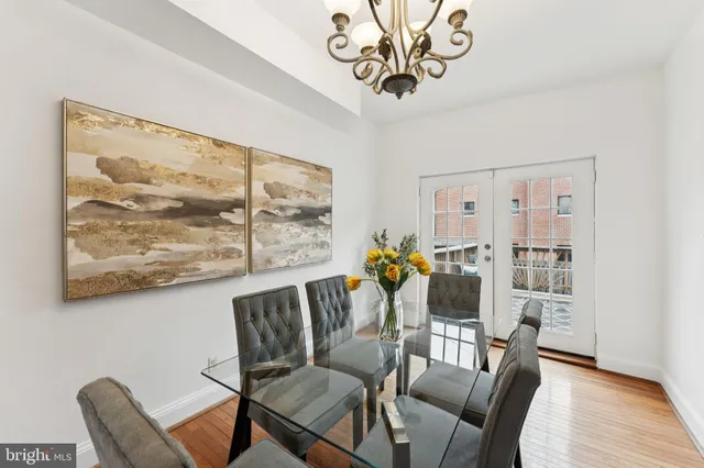 a dining room with wooden floor a chandelier a wooden table and chairs