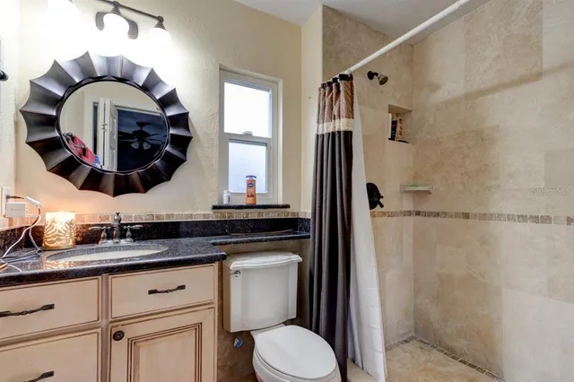 a bathroom with a granite countertop sink a mirror and a shower