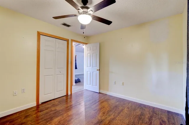 an empty room with wooden floor chandelier fan and closet area