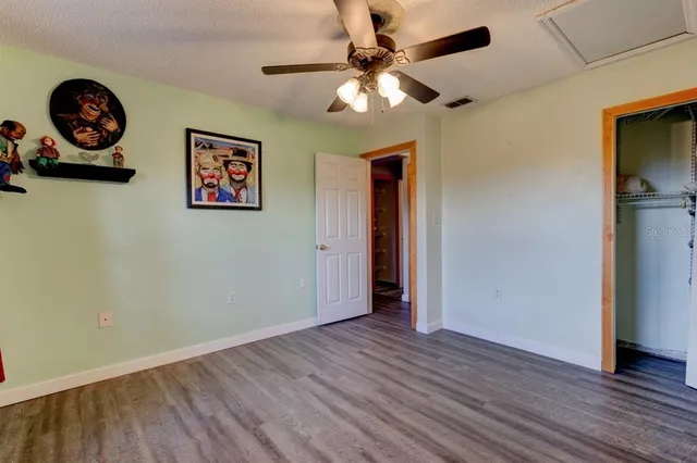 an empty room with wooden floor closet and fan