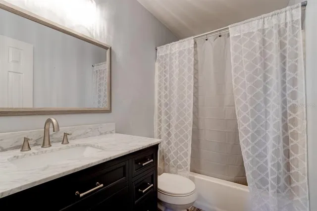 a bathroom with a granite countertop sink a toilet and a mirror