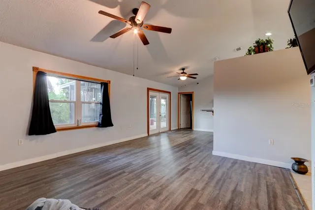 a view of an empty room with window and wooden floor