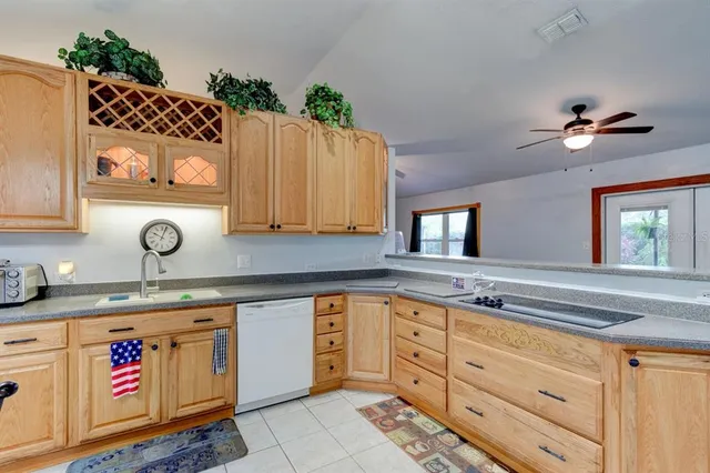 a kitchen with granite countertop a stove a sink and dishwasher wooden cabinets with granite countertops