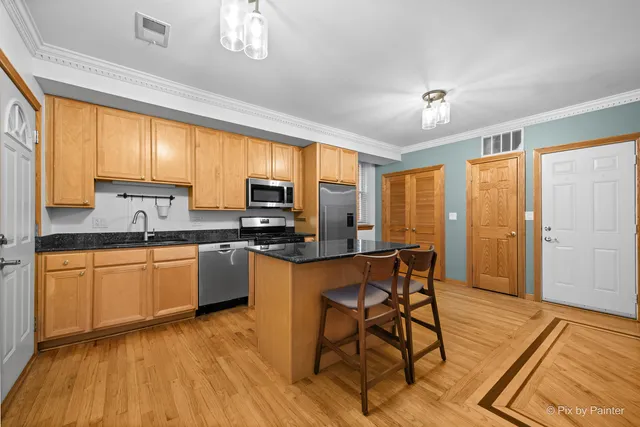 a kitchen with stainless steel appliances granite countertop a refrigerator a stove top oven and a dishwasher with wooden floor