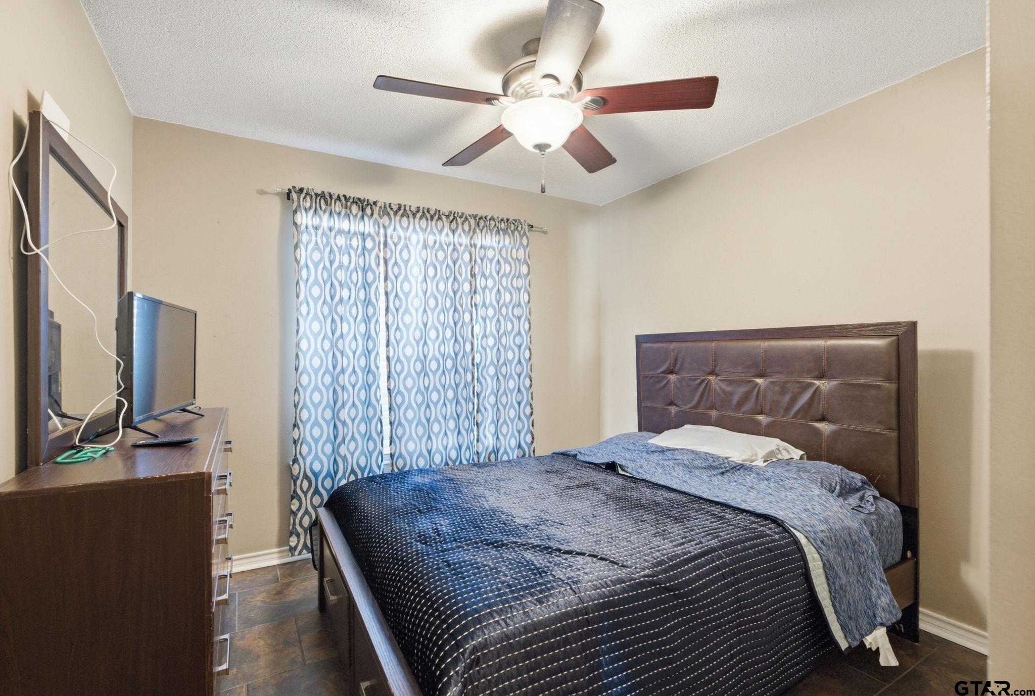 2301 McDonald Road Tyler, TX 75701 - Photo 15 of 26 a bedroom with a large bed and a flat tv screen