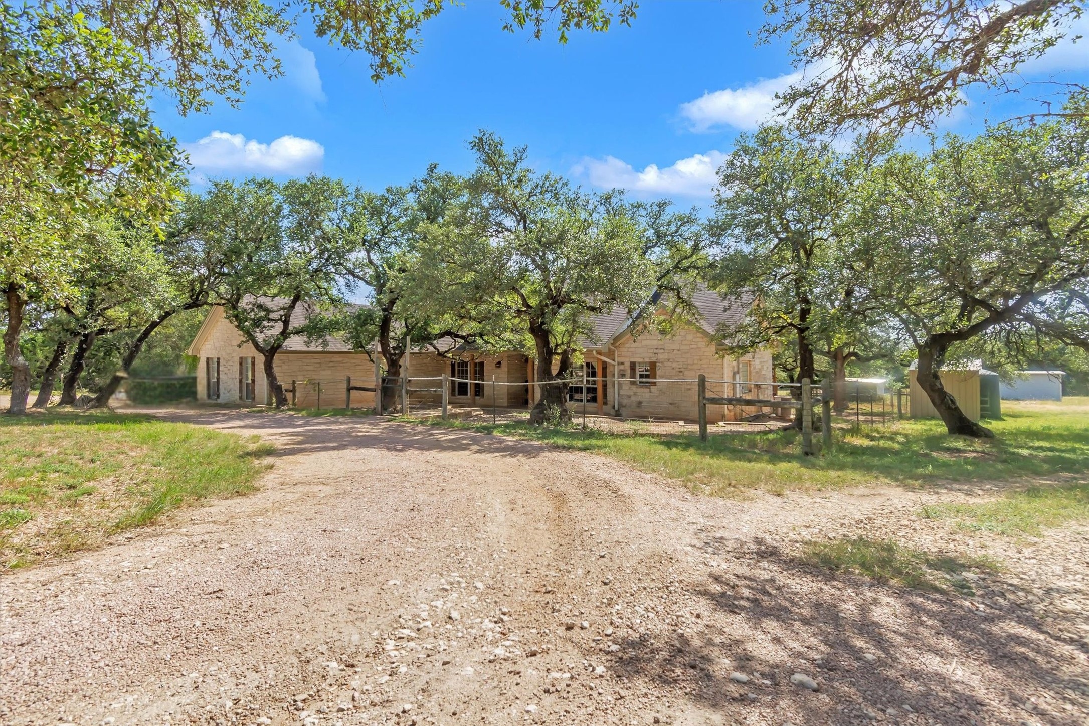 1120 Meadow Ridge Drive Austin, TX 78737 - Photo 3 of 40 A tranquil country estate beckons with a private drive leading to a stone facade home nestled among mature trees.