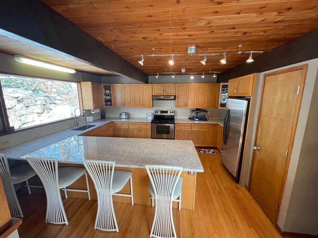 5 Clipper Way Beverly, MA 01915 - Photo 16 of 42 a kitchen with stainless steel appliances granite countertop a sink refrigerator dining table and chairs