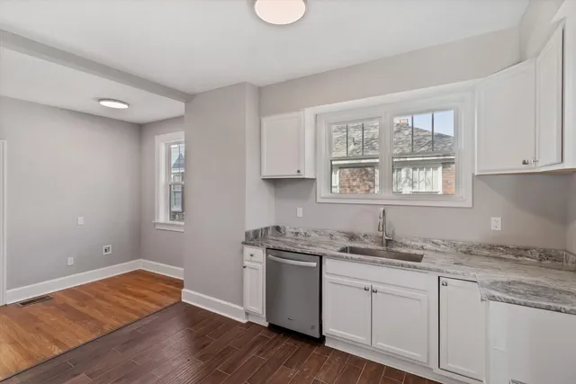 a kitchen with granite countertop white cabinets and wooden floor