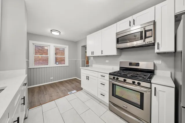 a kitchen with stainless steel appliances granite countertop white cabinets and window