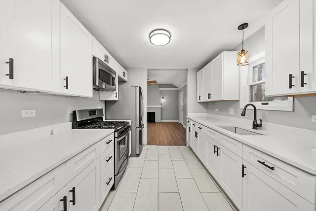 a kitchen with granite countertop a sink stainless steel appliances and white cabinets