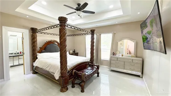 a bedroom with a bed a chandelier and a mirror on the dresser