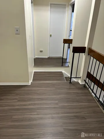 a view of an empty room with wooden floor and stairs