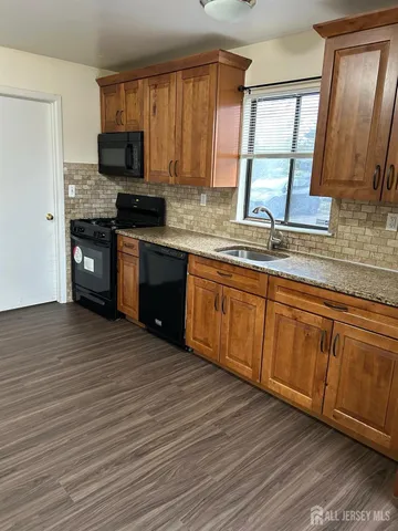 a kitchen with stainless steel appliances granite countertop wooden cabinets a stove top oven a sink and dishwasher with wooden floor